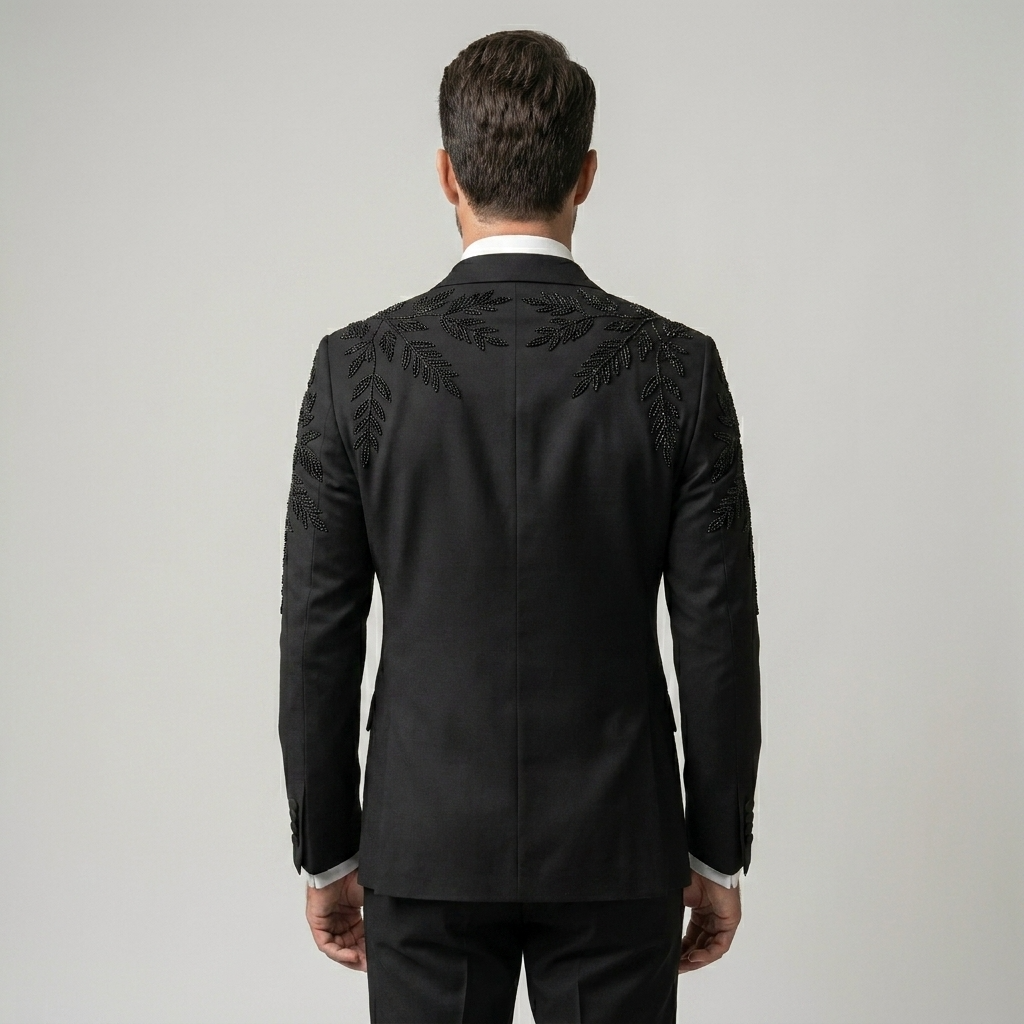 Man wearing a black suit with intricate embroidery on a plain background | Bespoke Black Double Breasted Tuxedo Jacket with Leaf Embroidery